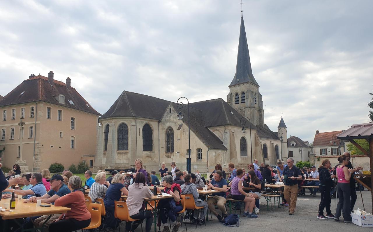 Randonneurs attablés place Saint-Paul à Jouarre devant l'église, lors de la randonnée gourmande d'avril 2025